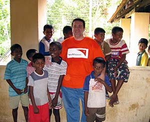 A World Vision volunteer poses for a picture with local children.